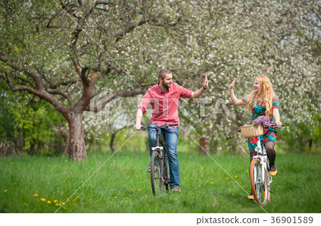 Loving young couple riding bicycles in the spring garden Loving young couple riding bicycles in the spring garden 36901589