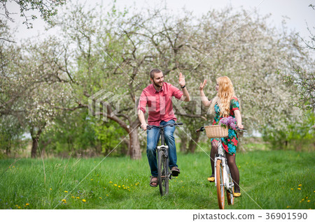 Loving young couple riding bicycles in the spring garden Loving young couple riding bicycles in the spring garden 36901590