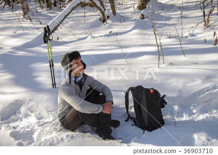 Young Man hiker in snowy forest take a rest during 36903710