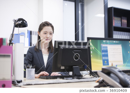 工作在一台個人計算機的年輕女性僱員在公司中 工作在一台個人計算機的年輕女性僱員在公司中 36910409