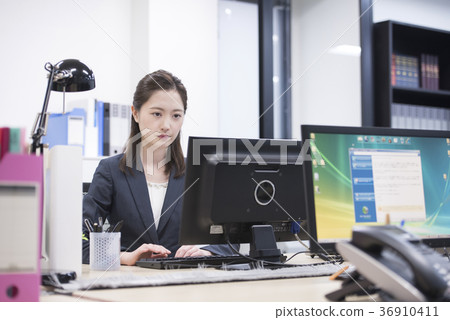 工作在一台個人計算機的年輕女性僱員在公司中 工作在一台個人計算機的年輕女性僱員在公司中 36910411
