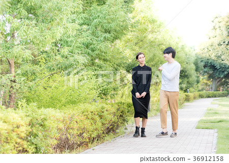 Men and women who walk on a fresh sidewalk with fresh greenery 36912158