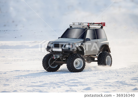 Off-road car with big wheels drives on snow Off-road car with big wheels drives on snow 36916340