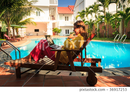 Girl Sits in Folding Chair with Laptop at Pool Girl Sits in Folding Chair with Laptop at Pool 36917253
