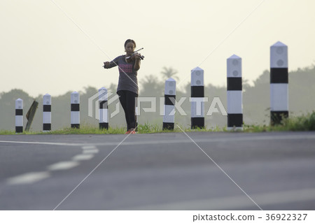 an asian woman is playing violin on the road side  36922327