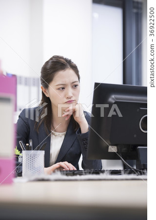 Young female employee worried looking at pc in office 36922500