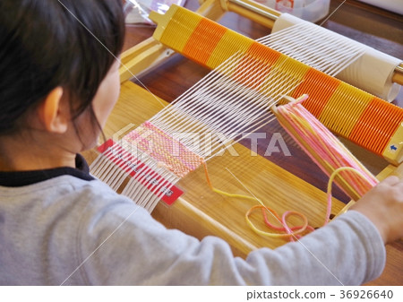 Child hand weaving a coaster with wool 36926640