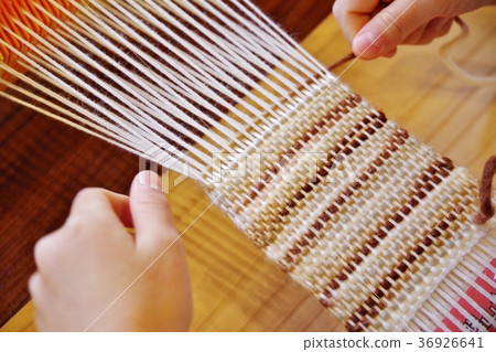 Child hand weaving a coaster with wool 36926641