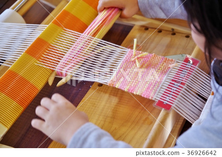 Child hand weaving a coaster with wool Child hand weaving a coaster with wool 36926642