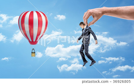 A tiny businessman held by a giant hand and 36926805