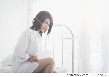 girl sitting on the bed with stomachache 36927017
