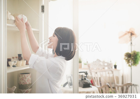 girl choosing ceramic cup in a white cupboard 36927031