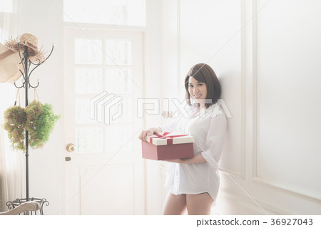 Asian girl open red gift box under sun light from a window Asian girl open red gift box under sun light from a window 36927043