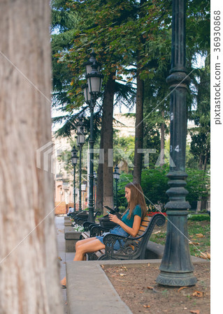 the girl sitting on the bench with the phone the girl sitting on the bench with the phone 36930868