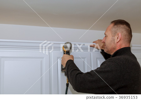 Handyman working using brad nail gun Moulding  36935153
