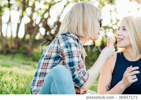 two young woman eating ice cream cones on hot two young woman eating ice cream cones on hot 36937171