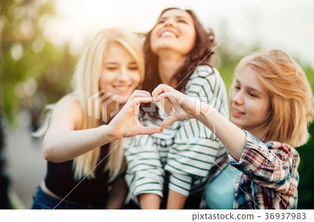 three female friends making heart shape from hand three female friends making heart shape from hand 36937983