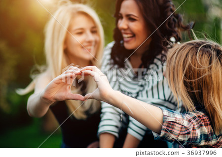three female friends making heart shape from hand 36937996