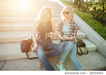 Two friends looking at pictures on a cellphone Two friends looking at pictures on a cellphone 36938002