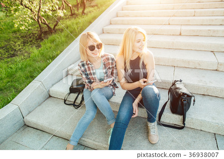 Two friends looking at pictures on a cellphone Two friends looking at pictures on a cellphone 36938007