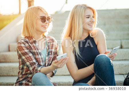Two friends looking at pictures on a cellphone 36938010