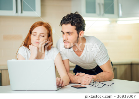 Couple Using Laptop On Desk At Home and think Couple Using Laptop On Desk At Home and think 36939307