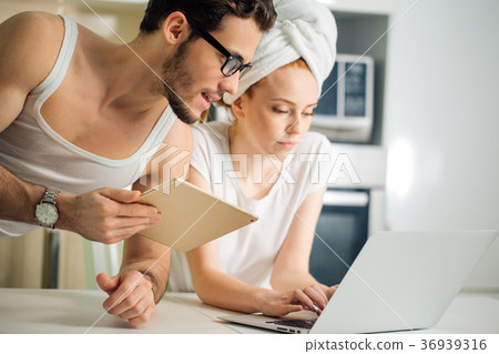 Couple with laptop and tablet in kitchen Couple with laptop and tablet in kitchen 36939316