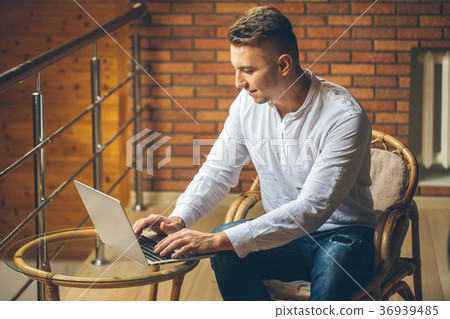 man sitting at home and working on laptop. male man sitting at home and working on laptop. male 36939485