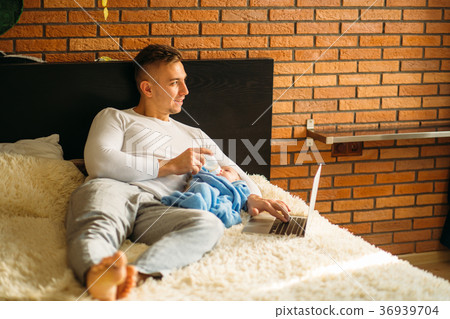 man feeding little baby while lying on bed and 36939704
