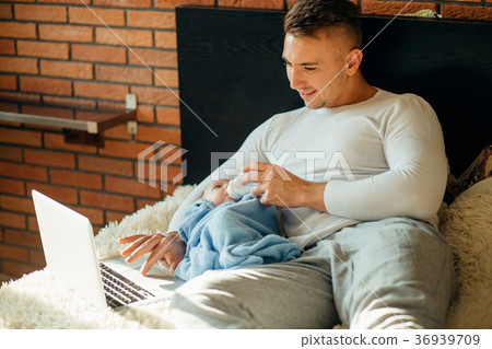 man feeding little baby while lying on bed and 36939709