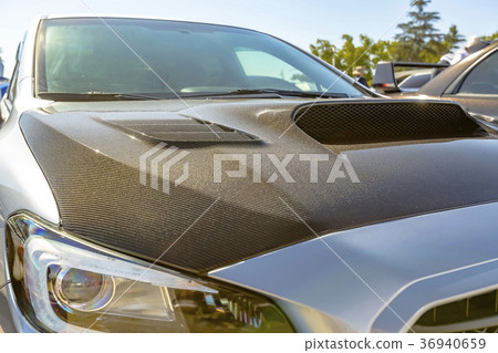 Carbon fiber hood on a white car Carbon fiber hood on a white car 36940659