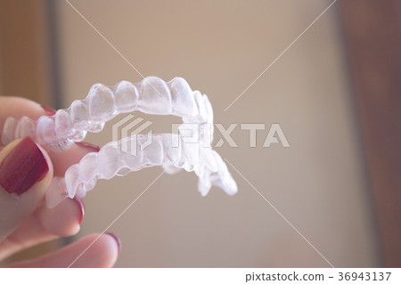Invisible dental orthodontics held by a woman 36943137
