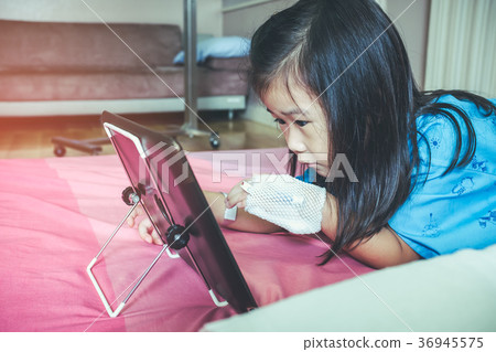 Cute asian child using tablet with iv drip on hand 36945575