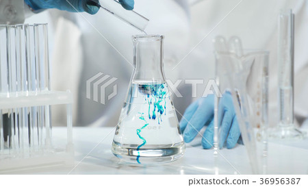 Chemist pouring substance into conical flask with Chemist pouring substance into conical flask with 36956387