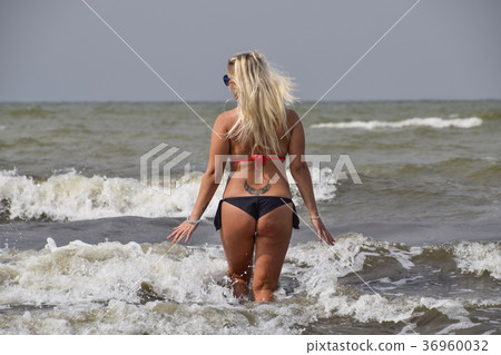 Beautiful blonde walks into the sea water Beautiful blonde walks into the sea water 36960032