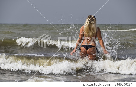 Beautiful blonde walks into the sea water Beautiful blonde walks into the sea water 36960034