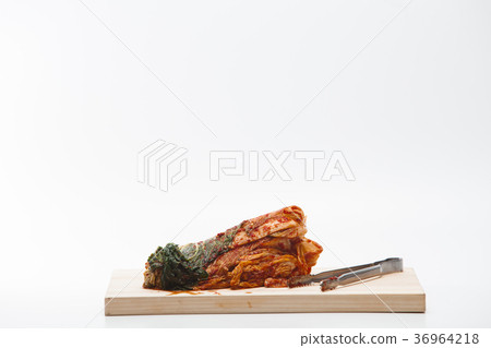 Kimchi and tongs on cutting board isolated 36964218