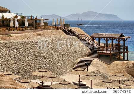 Beach by the sea with sun loungers and pier Beach by the sea with sun loungers and pier 36974578