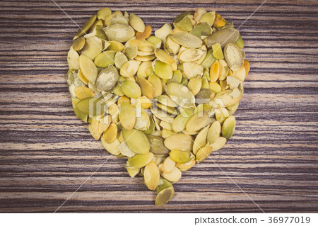 Heart of pumpkin seeds on wooden background 36977019