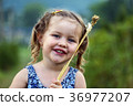 Little girl put wheat spikelets on the face 36977207
