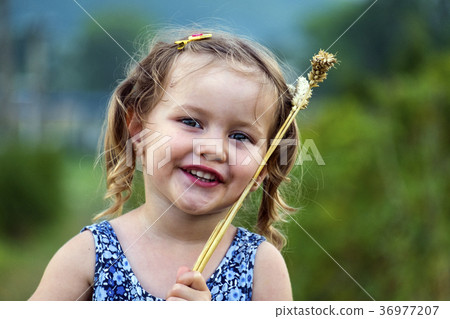 Little girl put wheat spikelets on the face 36977207