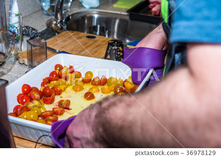 Male hand holding white ceramic baking tray with 36978129