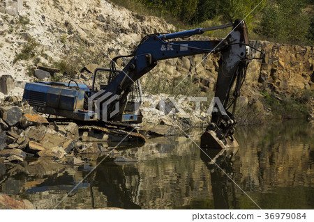 Broken excavator and basalt columns rocks. Heavy 36979084