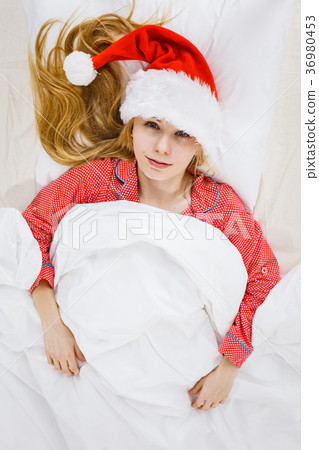Happy woman wearing pajamas and Santa Claus hat 36980453