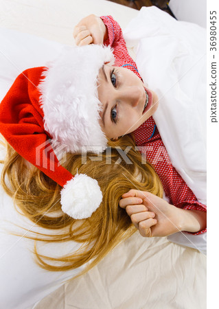 Happy woman wearing pajamas and Santa Claus hat Happy woman wearing pajamas and Santa Claus hat 36980455