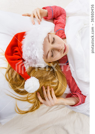 Happy woman wearing pajamas and Santa Claus hat Happy woman wearing pajamas and Santa Claus hat 36980456