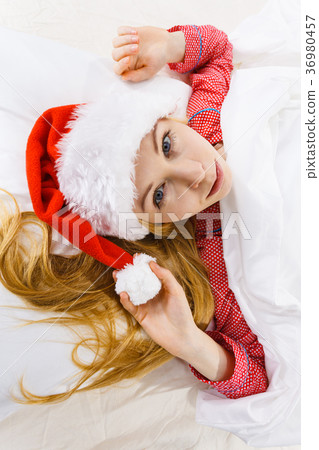 Happy woman wearing pajamas and Santa Claus hat Happy woman wearing pajamas and Santa Claus hat 36980457