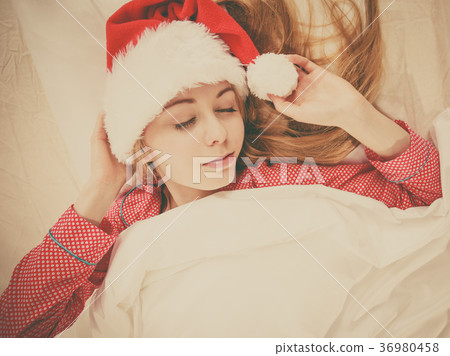 Happy woman wearing pajamas and Santa Claus hat Happy woman wearing pajamas and Santa Claus hat 36980458