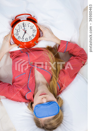 Sleeping woman wearing pajamas holding clock Sleeping woman wearing pajamas holding clock 36980463
