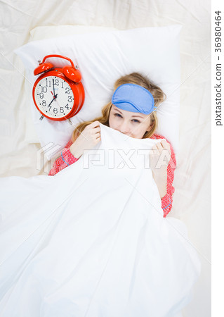 Sleepy woman wearing pajamas holding clock Sleepy woman wearing pajamas holding clock 36980464